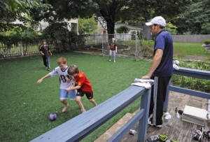 Family and children playing on artificial grass in the backyard