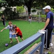 Family and children playing on artificial grass in the backyard