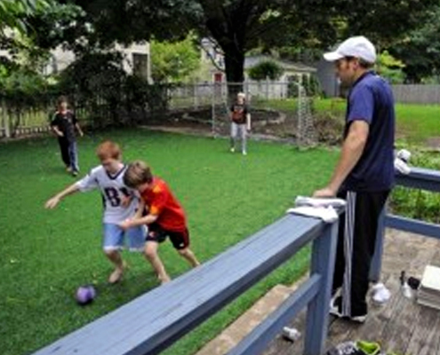 Family and children playing on artificial grass in the backyard